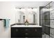 Bathroom showcasing a double sink vanity with black cabinets, elegant mirrors, and a glass-enclosed shower at 6512 Upham St, Arvada, CO 80003