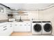Basement laundry room featuring front loading washer/dryer and modern white cabinetry at 6512 Upham St, Arvada, CO 80003