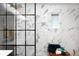Modern glass enclosed shower featuring marble-style tile and black accents at 6512 Upham St, Arvada, CO 80003