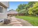 Spacious backyard with stone paver path, fire pit, and grassy area lined with mature trees at 1641 Cedarwood Dr, Longmont, CO 80504