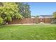 Fenced backyard with manicured lawn, gravel landscaping, and mature shade trees at 1641 Cedarwood Dr, Longmont, CO 80504