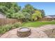 Cozy backyard featuring circular stone patio with fire pit, stone walkway, and shady trees at 1641 Cedarwood Dr, Longmont, CO 80504