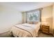 Neutral bedroom with a queen bed, side table, and a window with tree views at 1641 Cedarwood Dr, Longmont, CO 80504