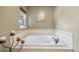 Bathroom featuring a large soaking tub with tile surround and a window for natural light at 7881 S Ivy Ct, Centennial, CO 80112