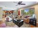 Open living room with comfortable leather seating, ceiling fan, and natural light at 7881 S Ivy Ct, Centennial, CO 80112