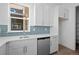 A modern kitchen featuring white cabinets, stainless steel dishwasher, blue backsplash, and quartz countertops at 5625 W 141St Ln, Broomfield, CO 80020