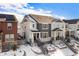 Two-story townhome with gray and white exterior, stone accents, and a snowy front yard at 9808 Rosalee Peak St, Littleton, CO 80125