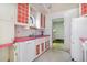 Quaint kitchen featuring red accents, vintage white cabinetry, and a stainless steel sink at 4730 Pierce St, Wheat Ridge, CO 80033