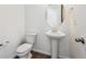 Bright half bath featuring a pedestal sink, oval mirror and white fixtures at 45934 Gentry Ave, Bennett, CO 80102