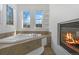 Relaxing main bathroom showcases a soaking tub, fireplace, and two windows providing light and style at 1204 S Balsam Ct, Lakewood, CO 80232