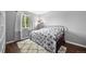 Cozy bedroom featuring wood floors, a window and a black metal bed frame topped with a patterned blanket and decor at 1482 S Pitkin Cir, Aurora, CO 80017