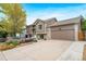 Well-maintained home featuring a spacious driveway, lush landscaping, and attractive tan exterior at 1482 S Pitkin Cir, Aurora, CO 80017