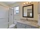 Well-lit bathroom with a granite countertop vanity, shower, and decorative mirror at 12671 Home Farm Ln, Westminster, CO 80234