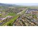 Expansive aerial view of a neighborhood with houses, green fields, a road running through it, and mountains in the background at 7927 Elmwood St, Littleton, CO 80125