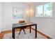 A simple office with desk and modern lamp, complemented by an art piece and natural light at 3469 Benton St, Wheat Ridge, CO 80212