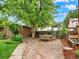 Private backyard patio with stone pavers, wooden dining set, and lush landscaping and a brick fence at 1247 Dexter St, Denver, CO 80220