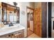 Cozy bathroom featuring a wood vanity with white countertop and custom mirror, creating a warm and inviting space at 266 Lodgepole Dr, Evergreen, CO 80439