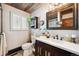 Bright bathroom with a rustic wood vanity, framed mirror, and window with plantation shutters for natural light at 266 Lodgepole Dr, Evergreen, CO 80439