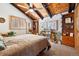 Inviting bedroom featuring a vaulted wood ceiling, rustic beams, and natural light from the windows at 266 Lodgepole Dr, Evergreen, CO 80439