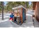 Brick outbuilding with a blue door, sitting in a snowy yard amongst trees at 266 Lodgepole Dr, Evergreen, CO 80439