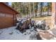 View of the home's garage exterior with covered equipment surrounded by snow and woods at 266 Lodgepole Dr, Evergreen, CO 80439