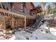 View of the home's exterior with stone accents, staircases, and snowy surroundings, showcasing architectural details at 266 Lodgepole Dr, Evergreen, CO 80439