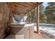 Outdoor hot tub on a bricked deck, perfect for relaxation amidst a scenic, snow-filled wooded setting at 266 Lodgepole Dr, Evergreen, CO 80439