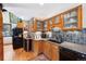 Well-lit kitchen featuring granite countertops, wooden cabinets, and black appliances at 266 Lodgepole Dr, Evergreen, CO 80439