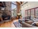 Inviting living room with stone fireplace, large windows, wood floors, and a comfortable gray sectional couch at 266 Lodgepole Dr, Evergreen, CO 80439