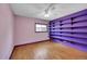 Bedroom with wood floors and purple shelves, illuminated by a ceiling fan and natural light through the window at 3145 S Bryant St, Englewood, CO 80110
