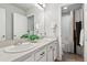 Modern bathroom featuring double sinks, white cabinets, and a shower-tub combo with stylish curtain at 17949 W 94Th Dr, Arvada, CO 80007