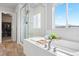 Bright bathroom featuring a bathtub, glass shower, and exterior view at 17949 W 94Th Dr, Arvada, CO 80007
