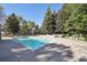 Outdoor pool surrounded by trees, seating, and tables with umbrellas under a clear blue sky at 857 S Van Gordon Ct # B107, Lakewood, CO 80228