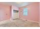 Bright bedroom featuring pink walls, carpet flooring, and a closet with shelving, offering a cozy space at 1888 Ruby Ct, Brighton, CO 80603