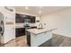 Stylish kitchen with stainless steel appliances, a kitchen island, and dark cabinetry with barstool seating at 1888 Ruby Ct, Brighton, CO 80603