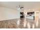 Open-concept living space featuring hardwood floors, ceiling fan, and access to kitchen with dark cabinets at 1888 Ruby Ct, Brighton, CO 80603