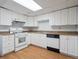 Well-lit kitchen with wooden floors, white cabinets, and white appliances at 2653 S Harrington Ln, Lakewood, CO 80227