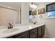 Modern bathroom featuring double sinks, a white countertop, dark cabinetry, and artistic decorations at 16002 E 111Th Cir, Commerce City, CO 80022