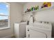 Bright laundry room with white washer and dryer, a large window, and white shelving at 16002 E 111Th Cir, Commerce City, CO 80022