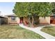 Charming brick home featuring a well-maintained lawn, mature tree and inviting front porch with red chairs at 2211 Lamar St, Edgewater, CO 80214