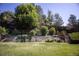 Landscaped backyard featuring a multilevel wooden retaining wall, lush greenery and a grassy lawn at 10856 Parker Vista Ln, Parker, CO 80138