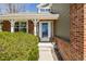 Close-up of a front porch with brick accents, a glass-paneled door, hanging plants, and well-maintained shrubs at 10856 Parker Vista Ln, Parker, CO 80138