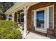 Charming front porch with brick details, hanging plants, a glass-paneled door, and cozy wicker furniture at 10856 Parker Vista Ln, Parker, CO 80138