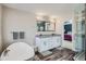 Bathroom featuring a white vanity, double sinks, modern fixtures, and a soaking tub at 7998 E Vassar Dr, Denver, CO 80231