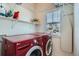 Well-equipped laundry room features a red washer/dryer and ample shelving for storage at 7998 E Vassar Dr, Denver, CO 80231