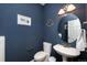 Stylish powder room with a blue wall, a pedestal sink, and decorative mirror at 3661 S Perth Cir # 6-101, Aurora, CO 80013