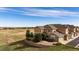 Inviting townhome exterior with neutral siding, mature landscaping, and a retaining wall, set against an expansive field at 3661 S Perth Cir # 6-101, Aurora, CO 80013