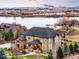 Captivating exterior shot of the home featuring stone accents, a covered porch, and beautiful lake views at 12648 Waterside Ln, Longmont, CO 80504