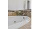 Close up of white soaking tub with travertine tile surround at 7470 S Steele Cir, Centennial, CO 80122