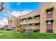 Brick apartment building with awnings, set against a blue sky and green lawn at 1454 Jersey St # 104, Denver, CO 80220
